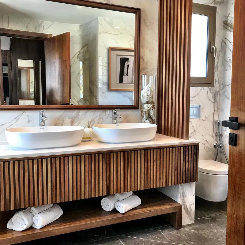 Salle de bains : double vasque blanche, meuble à lames de noyer, marbre Calacatta